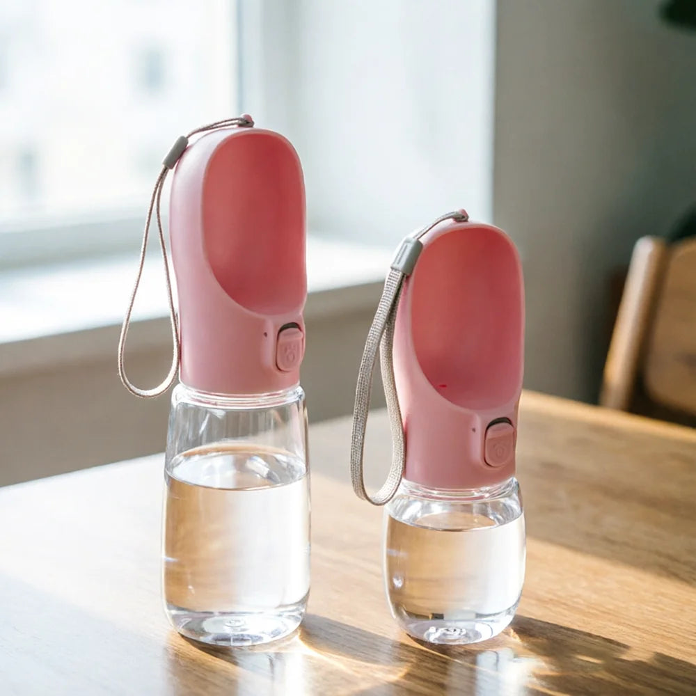Two pink trail bottles filled with water on a wooden table